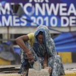 An Indian woman works in front of a torn Commonwealth Games banner in New Delhi on September 23, 2010