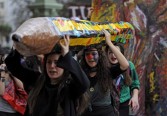 Three art students hold a giant pencil as they march along Mayo Avenue during a demonstration with teachers, in Buenos Aires