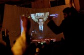 Protesters watch Egyptian President Hosni Mubarek give a speech on a projected television screen in Tahrir Square
