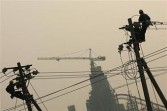 Workers fix wires on a wire pole along a road on March 31, 2006 in Beijing, China.