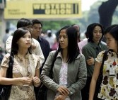 Office employees walk past a logo of remittance bank Western Union at the financial district of Manila on July 20, 2009.