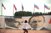 A youth takes a photo of a banner featuring portraits Russian President Dmitry Medvedev (L) and Prime Minister Vladimir Putin on July 4, 2011