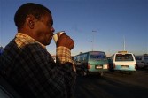 A minibus tax owner drinks an early morning cup of coffee at a taxi rank in Khayelitsha, Cape Town 29 January 2004. 