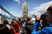 A tourist takes a photo from an open top bus as it passes Tower Bridge during a bus tour in London, U.K., on Thursday, May 21, 2009. 