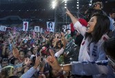 Yingluck Shinawatra raises her arm with a trademark salute, showing the sign of her party being first on the ballot sheet, to a large crowd of supporters 