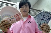 Chinese singer Hu Yenpin displays banknotes of Taiwanese and Chinese currency at a bank in Taipei on June 30, 2008.