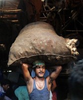 An Indian labourer carries a sack of vegetables on his head at a wholesale market in Kolkata on September 14, 2011