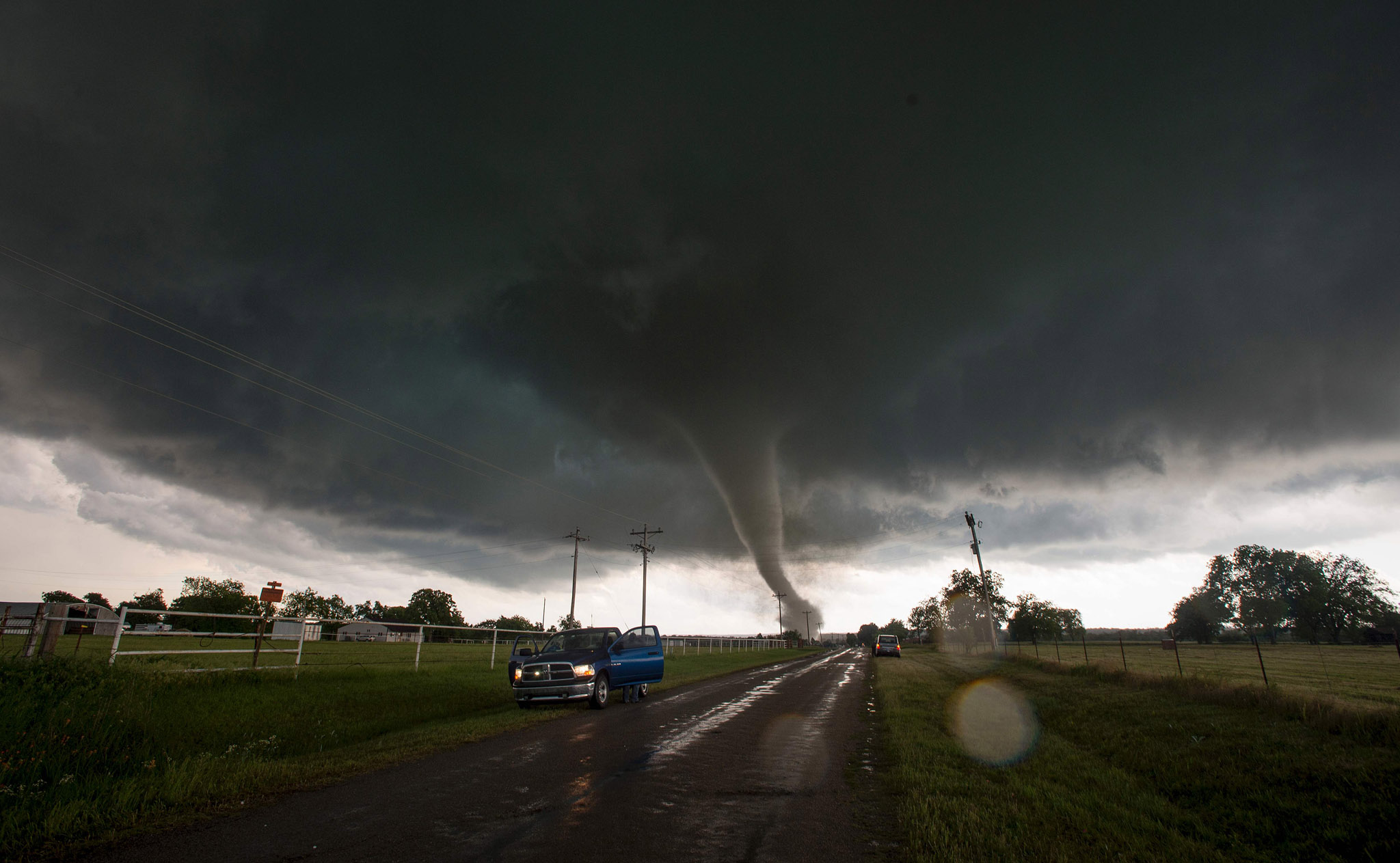on the side of a road as a tornado rips through a residential area after to...