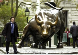 A man walks past the charging bull statu