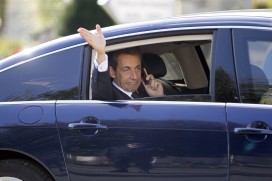 France's President Nicolas Sarkozy waves as he makes a call from his car after a meeting in western France, October 20, 2011. REUTERS/Charles Platiau 